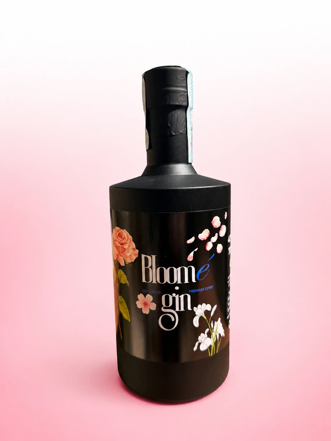 Bottiglia di Bloomé gin, vetro nero opaco con etichetta floreale, su fondo rosa