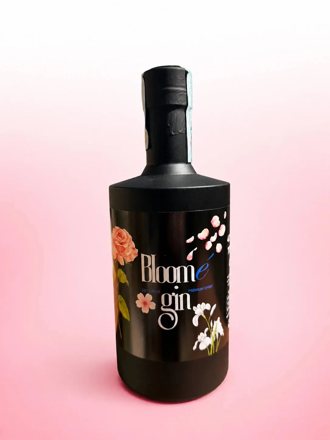 Bottle of Bloomé gin, matte black glass with a floral label, on a pink background